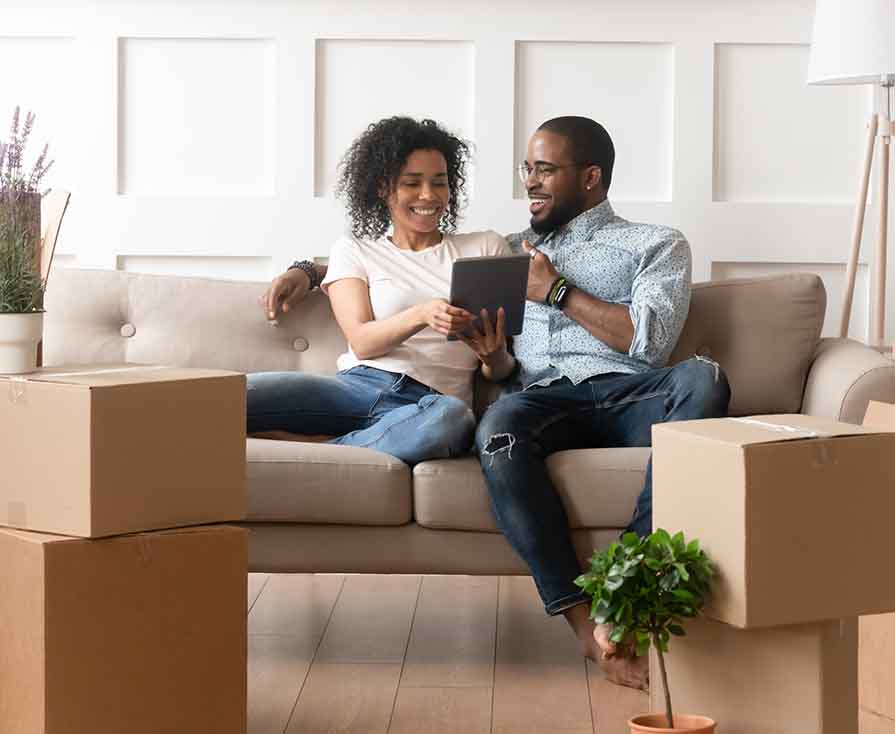 Smiling black couple use digital tablet on moving day