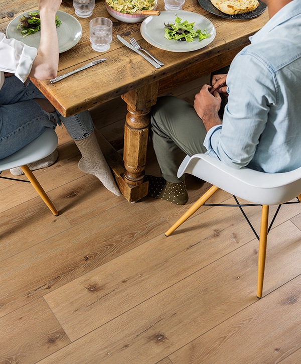 People seated at a dining table, sitting on top hardwood floors.